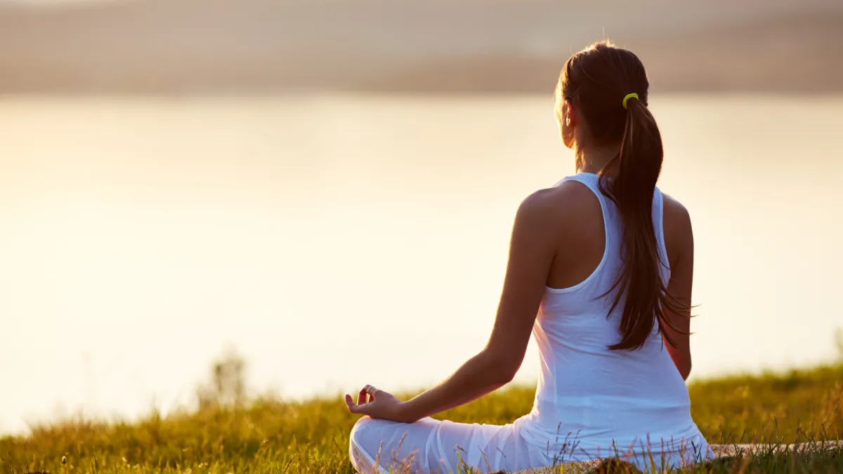 Femme pratiquant la méditation ou la respiration profonde pour réduire le stress et soulager les douleurs de fibromyalgie.