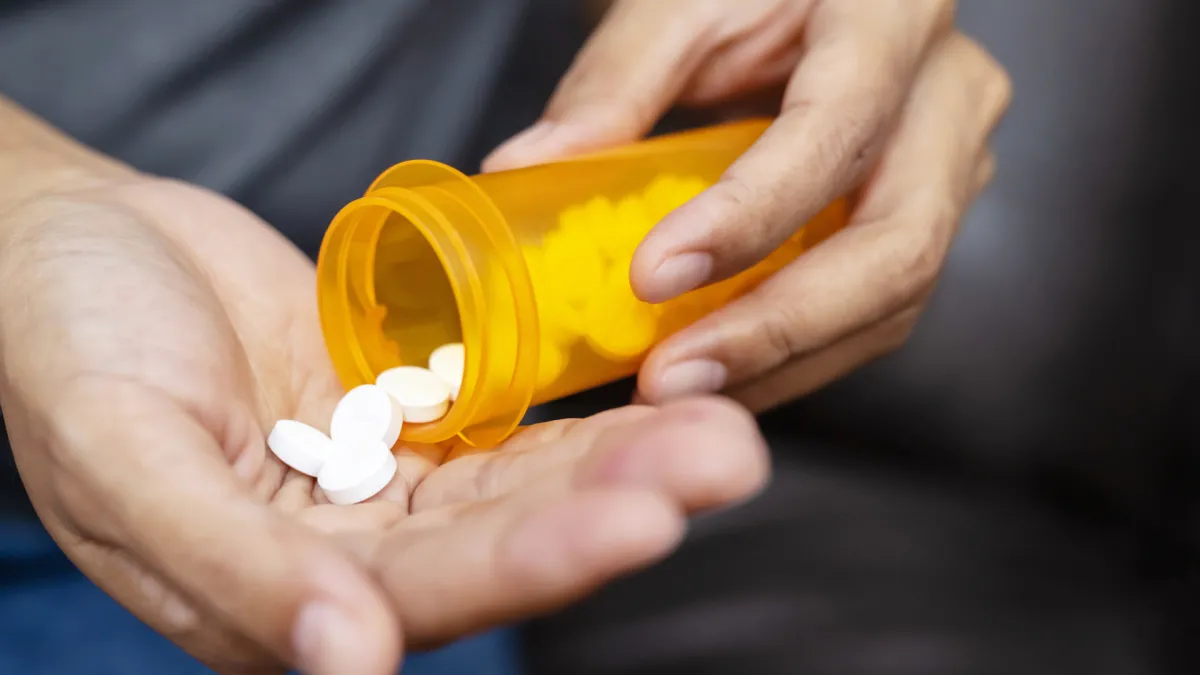 Personne tenant des médicaments contre le mal de dos — surconsommation d’anti-inflammatoires et risques liés à l’automédication.