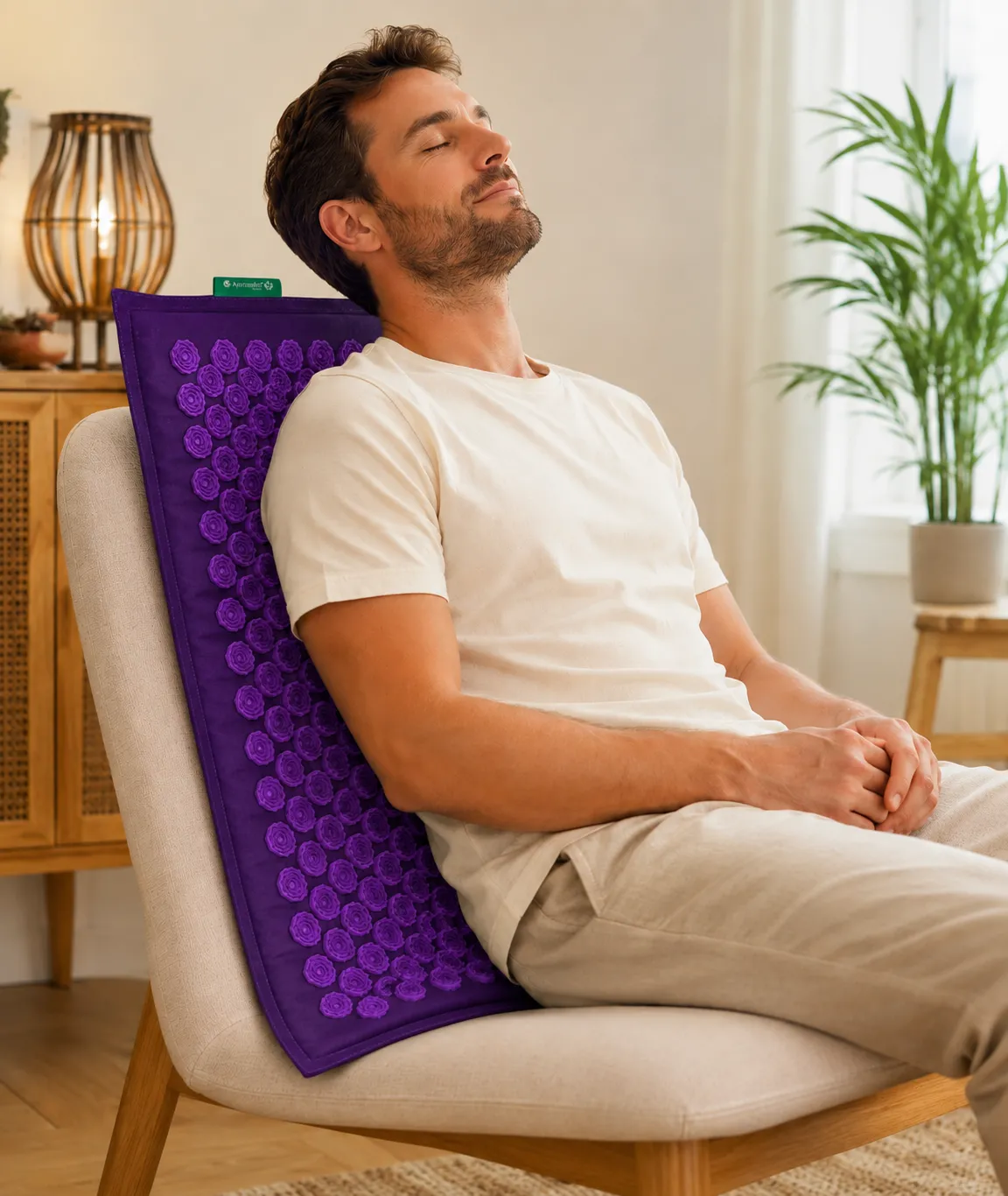 Homme se relaxant sur une chaise avec tapis d'acupression violet Ayurcomfort